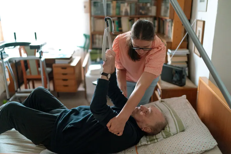 A physical therapist working with an older man on leg exercises at home
