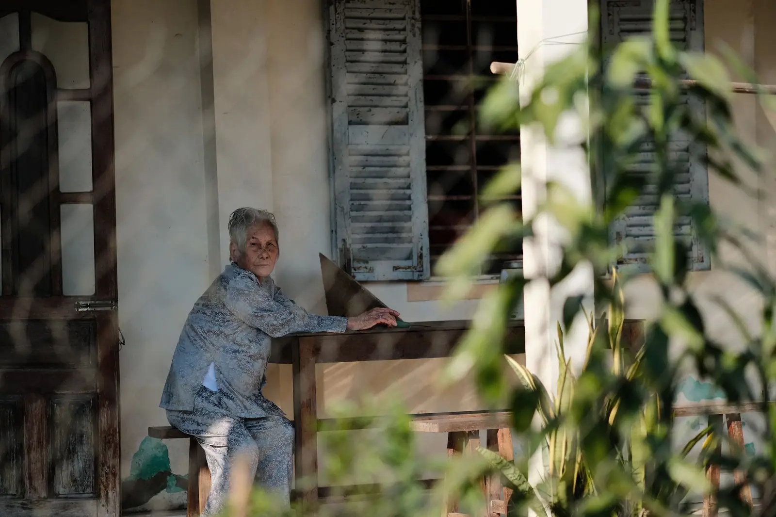 An older woman on the wooden porch of her old family home