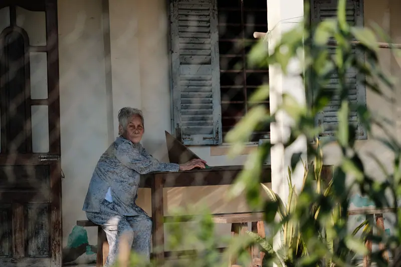 An older woman on the wooden porch of her old family home
