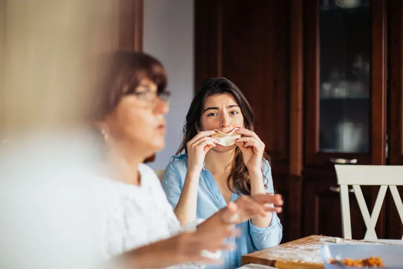 Two women laughing over lunch at the kitchen table
