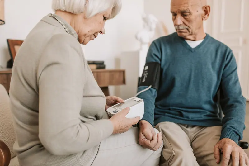 An older couple checking blood pressure together in their sitting room