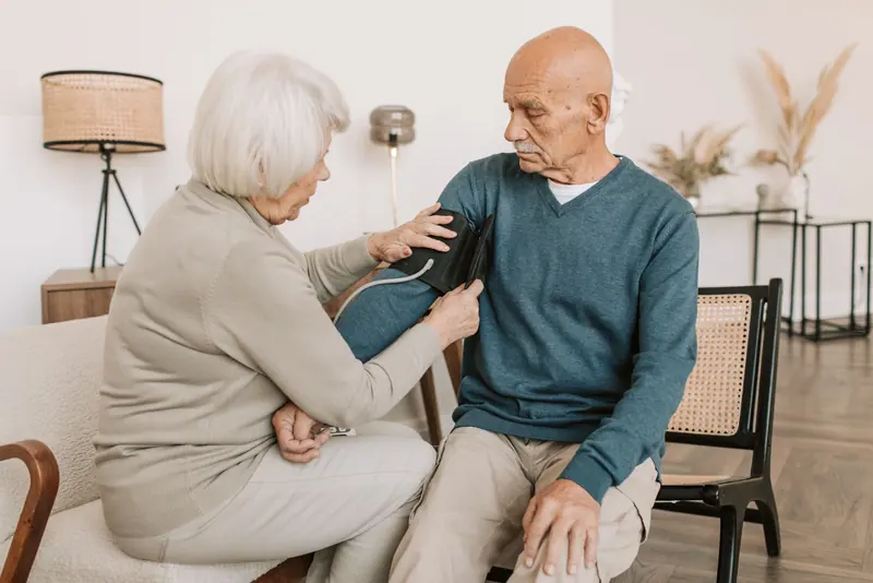 An older couple checking blood pressure together at home