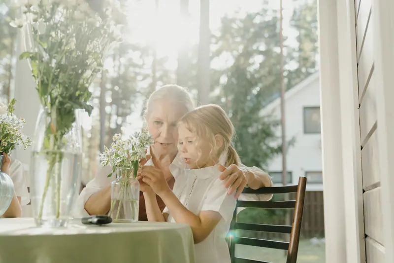 A grandmother and grandchild arranging flowers on the porch
