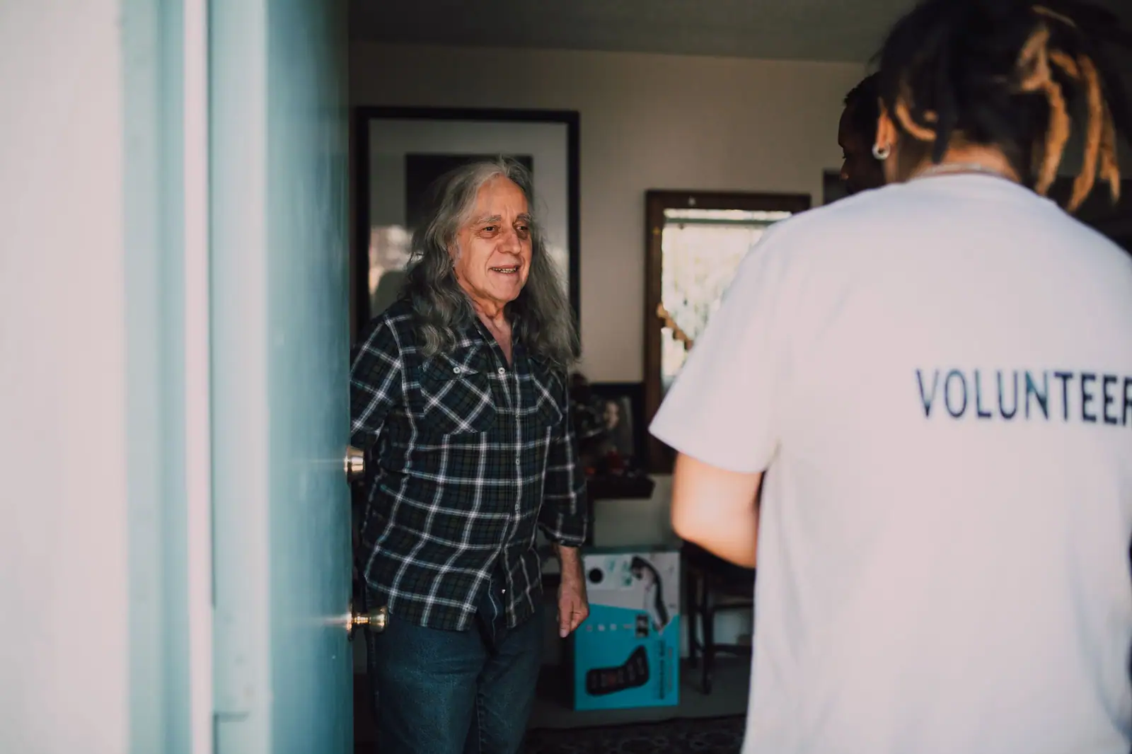 An older woman welcoming a visitor at her front door