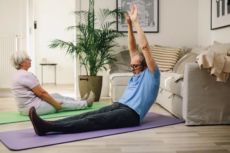 An older couple doing floor exercises in their living room