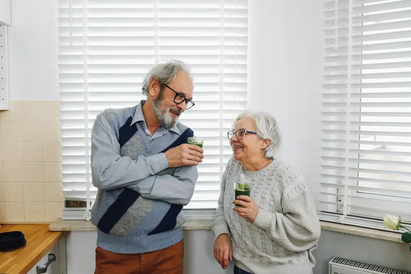 An older couple sharing a laugh in their kitchen