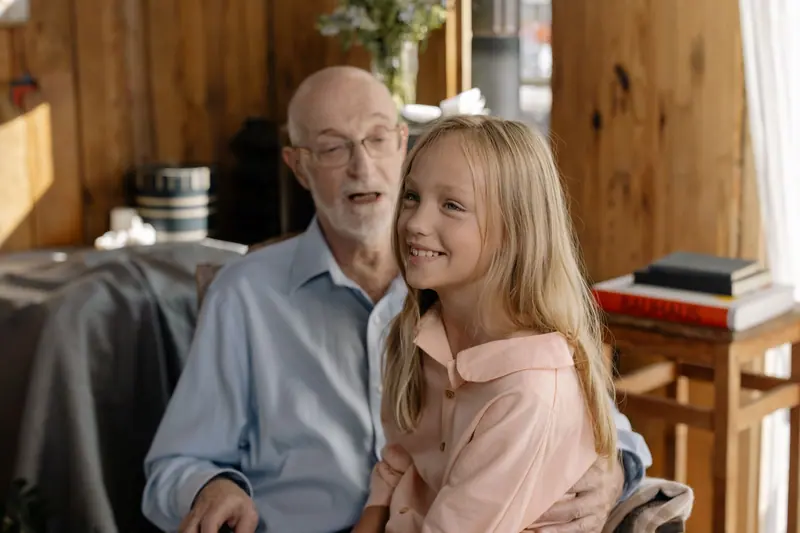 A resident and his granddaughter laughing in his room