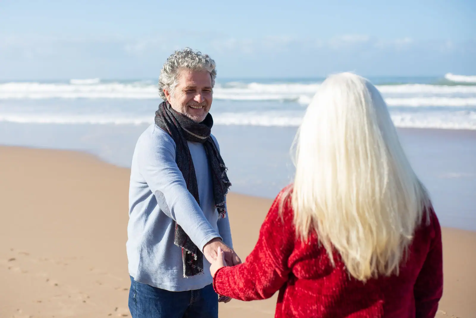 An older couple walking hand in hand on the sand