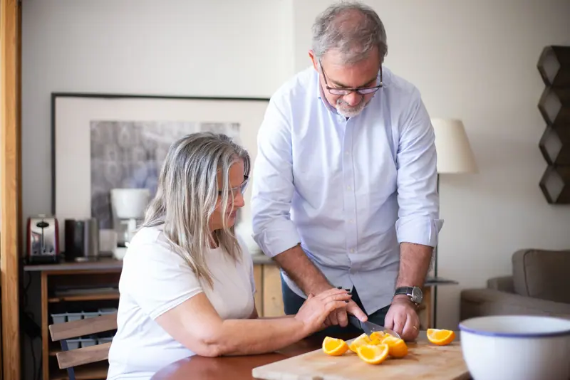 An older couple slicing oranges together in their kitchen