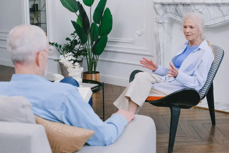 A resident and his wife talking in the parlor