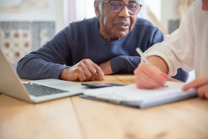 An older man signing his care plan at the dining table