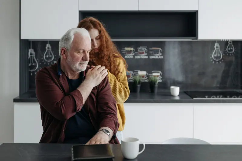 Emotional scene of a father and daughter sharing a tender, supportive moment in a modern kitchen.