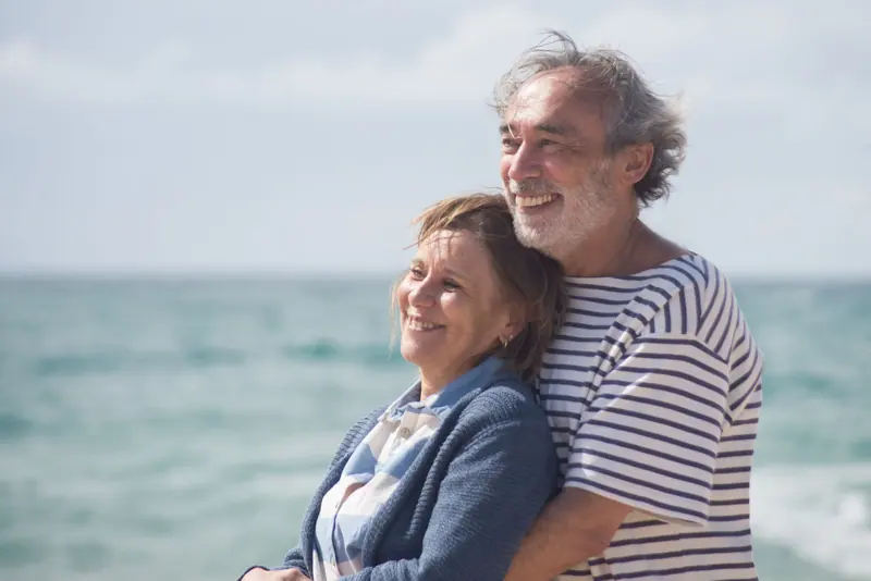 An older couple smiling together by the water
