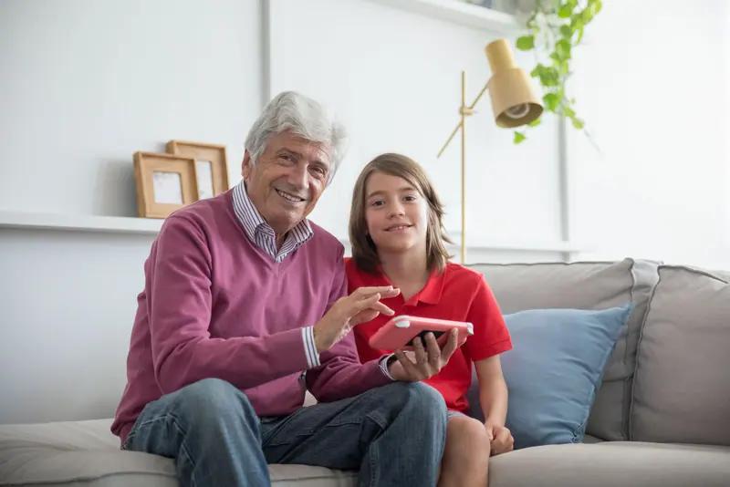 A grandfather and granddaughter looking at a tablet together