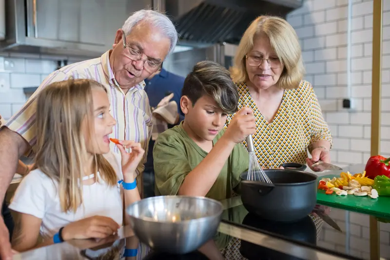 A resident couple cooking with their grandchildren on family day
