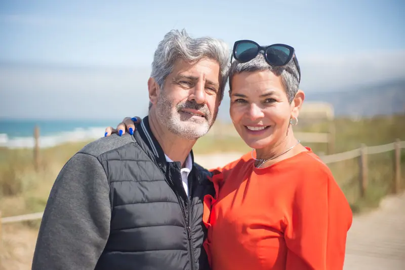 An older couple smiling on a sunny beach path