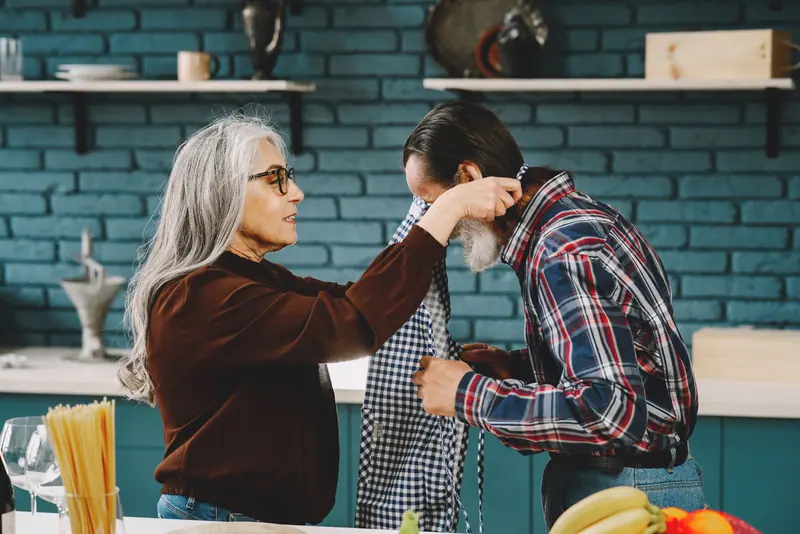 An older woman straightening her husband's apron