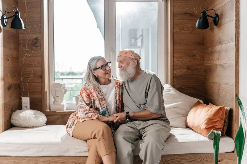 An older couple sitting close together on the sofa