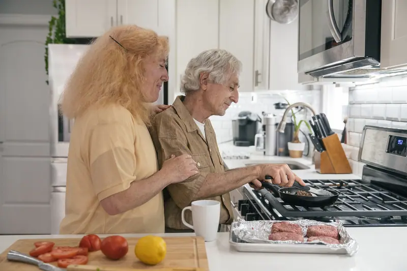 An older couple cooking supper together in their kitchen