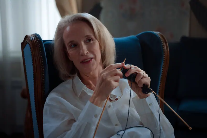 An older woman knitting in her wingback chair