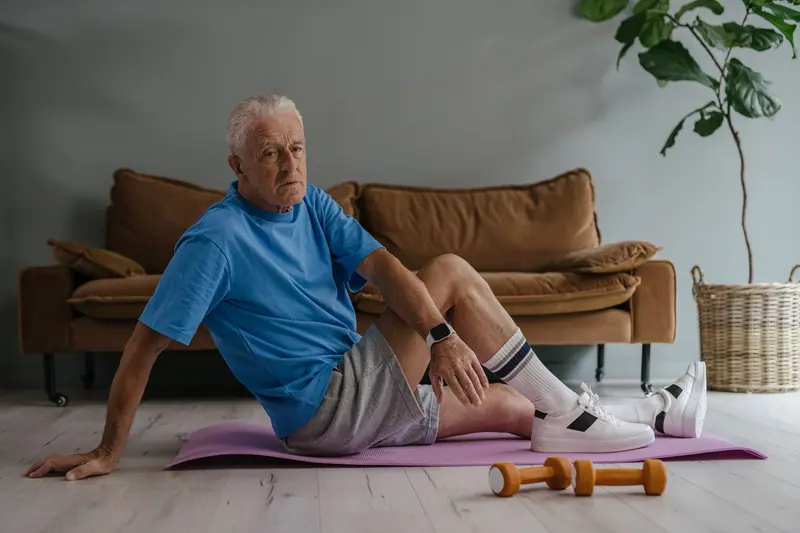 An older man doing floor exercises on a mat in his living room