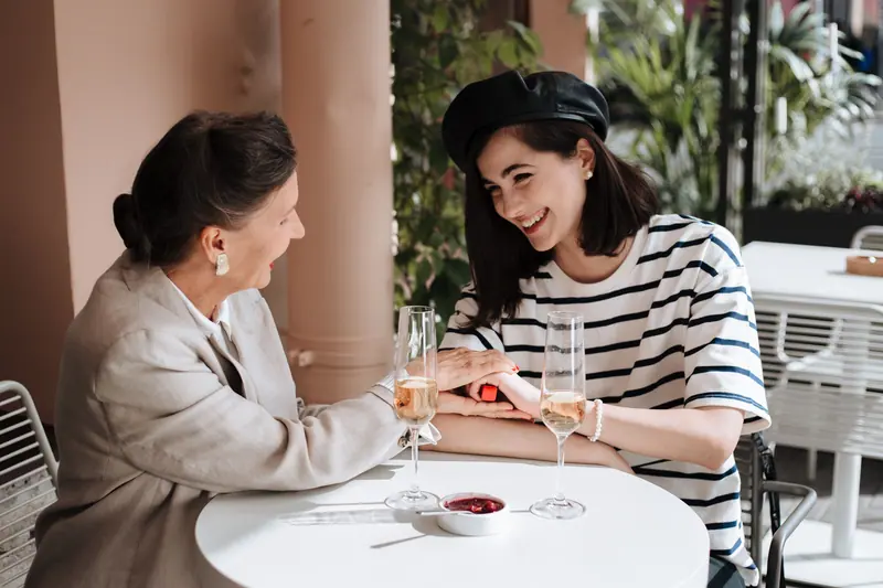 A mother and daughter laughing at a café table