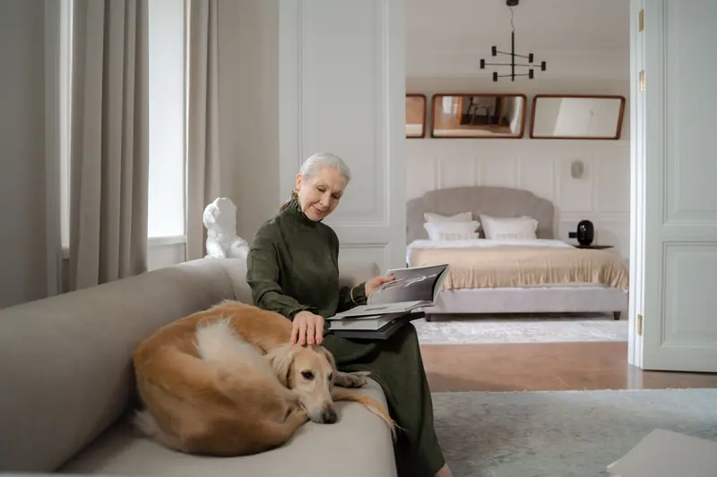 A woman reading as her greyhound leans in