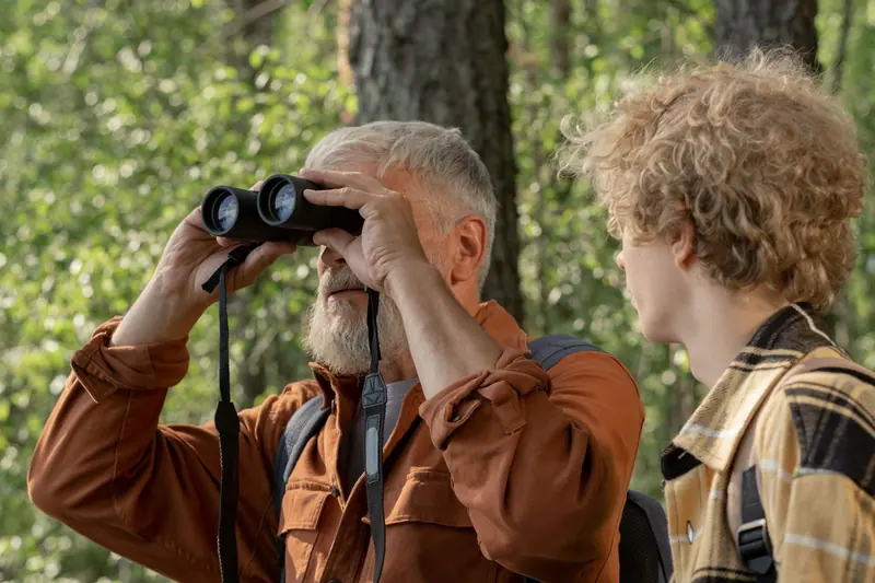A grandfather looking through binoculars with his grandson beside him