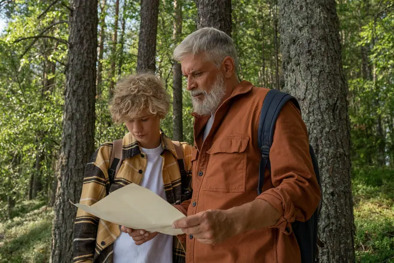 A grandfather and grandson reading a trail map in the woods