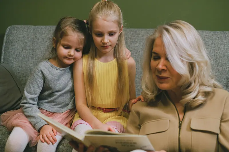 A grandmother reading with her two granddaughters