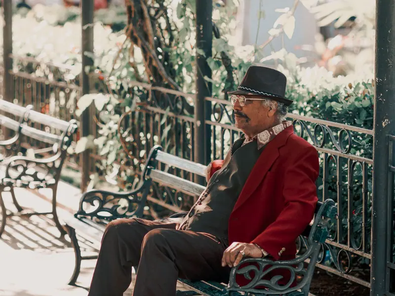A grandfather in his good hat resting on a park bench