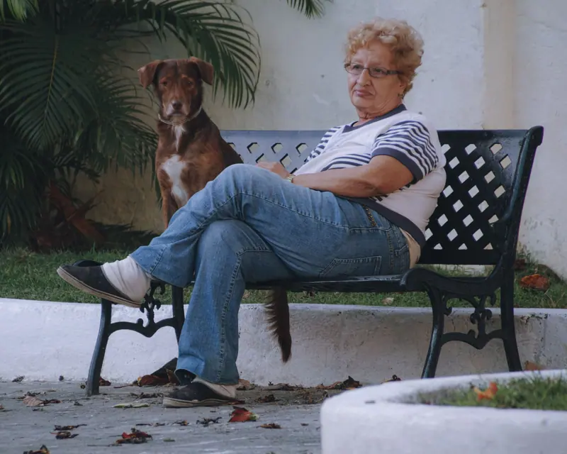 A woman resting on a garden bench with her dog