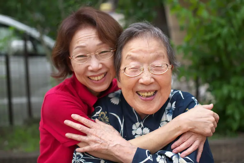 A daughter hugging her mother outside their home