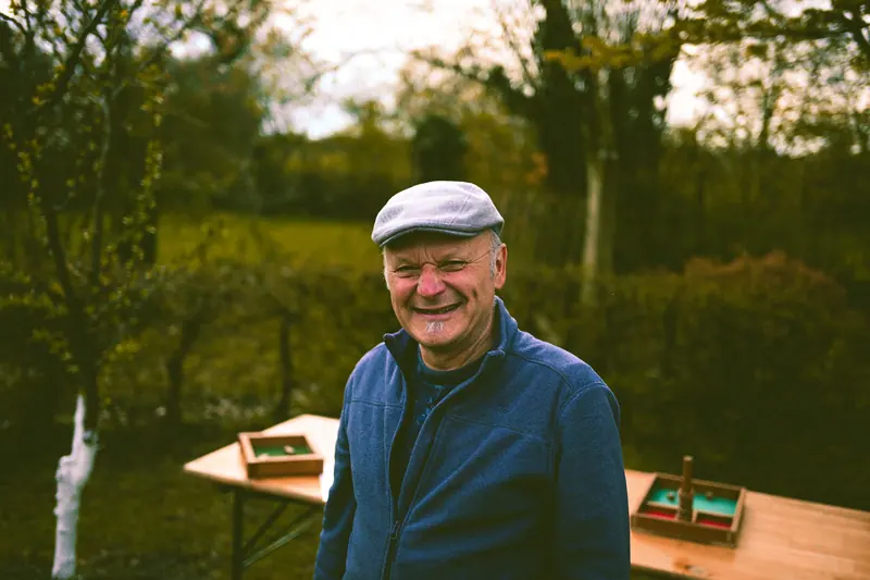 A grandfather in a flat cap laughing in the garden