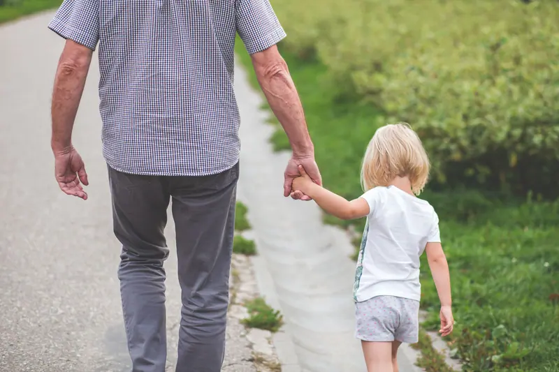 A grandparent and a little one walking hand in hand