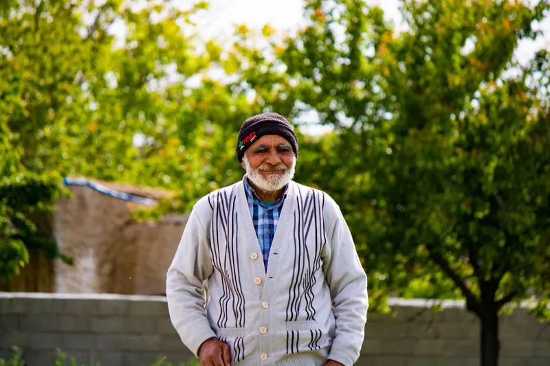 A patient standing in his orchard in a cardigan and knit cap