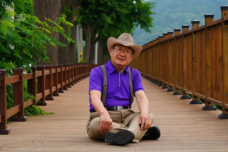 A man in a cowboy hat on a wooden footbridge