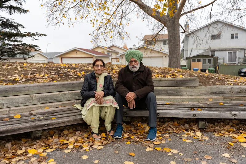 A married couple on a park bench in fall