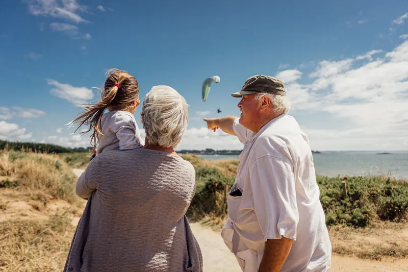 Grandparents and their granddaughter looking out over the water
