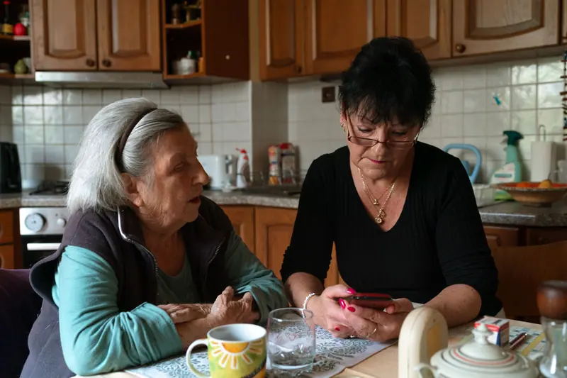 A daughter and mother talking over coffee at the kitchen table