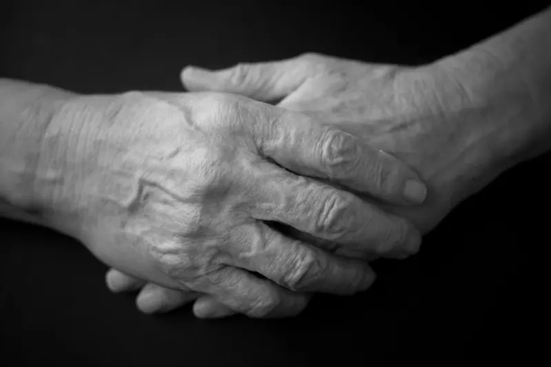 Two weathered hands resting together, in black and white