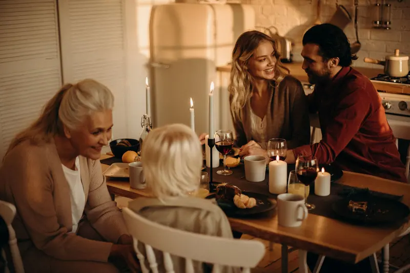 A family laughing over supper by candlelight