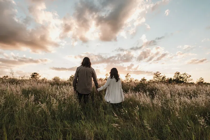 A couple walking hand in hand through the grass