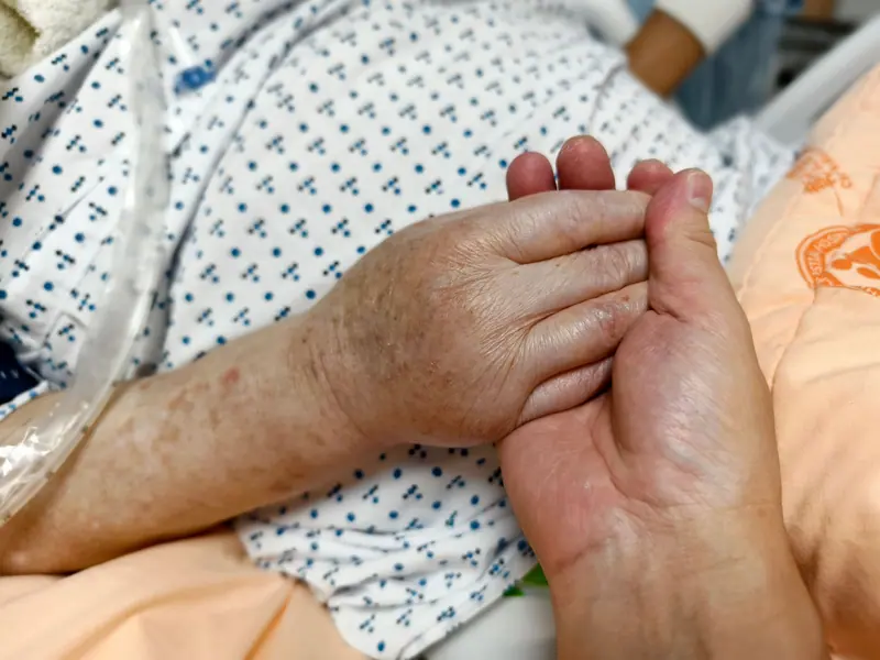 A nurse holding a patient's hand
