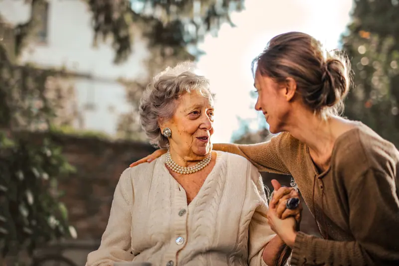 A hospice social worker laughing with a patient on the back porch