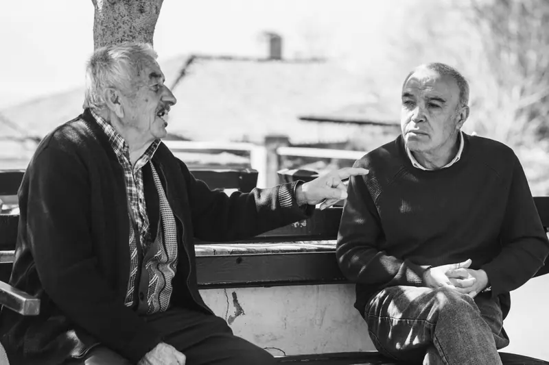 Two old friends talking outdoors, in black and white