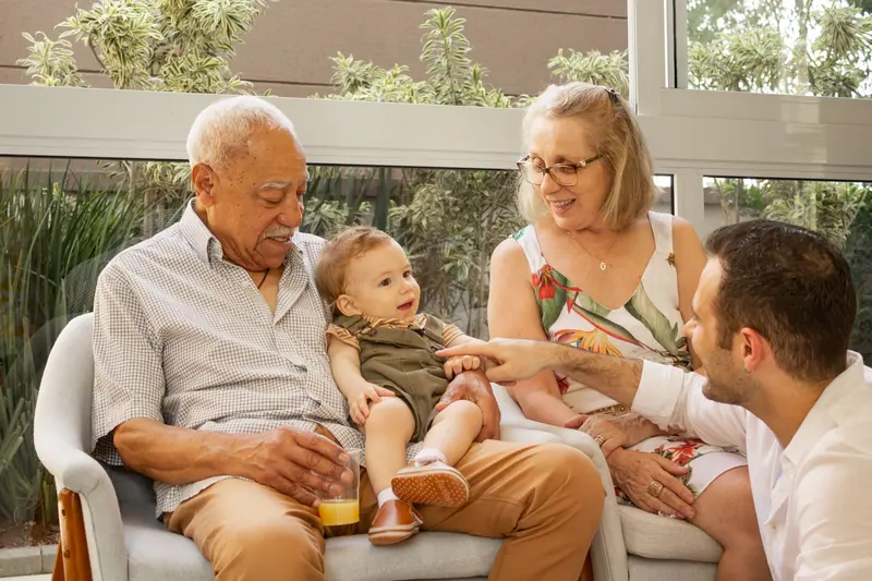 A grandfather sitting with his family and the newest grandbaby