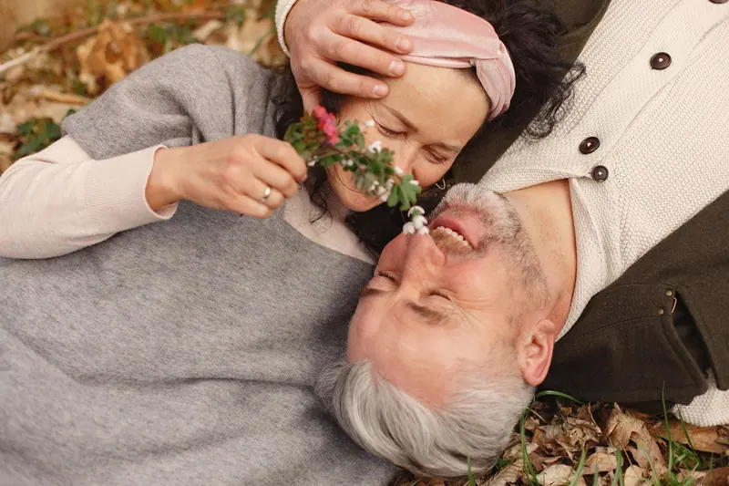 A daughter tickling her father's nose with a wildflower