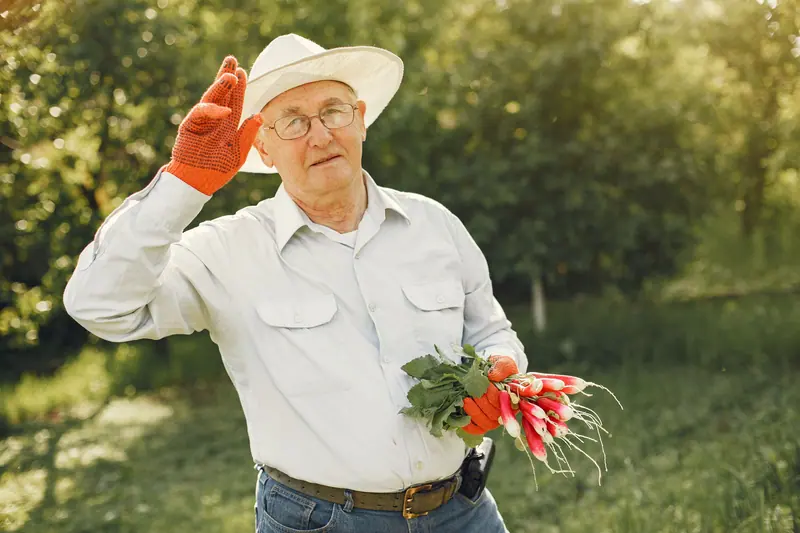 A patient in his straw hat holding up a bunch of radishes from his garden