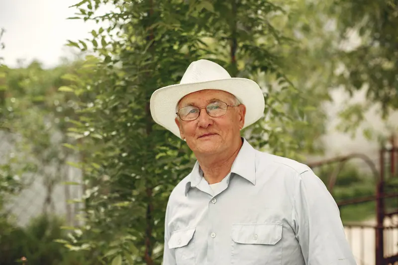 A man in a white hat among the trees
